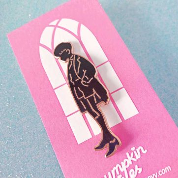 black colored enamel pin with gold metal of a school boy