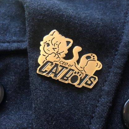 Gold colored enamel pin in a shape of a cute anime nekoboy saying "ceo of catboys"